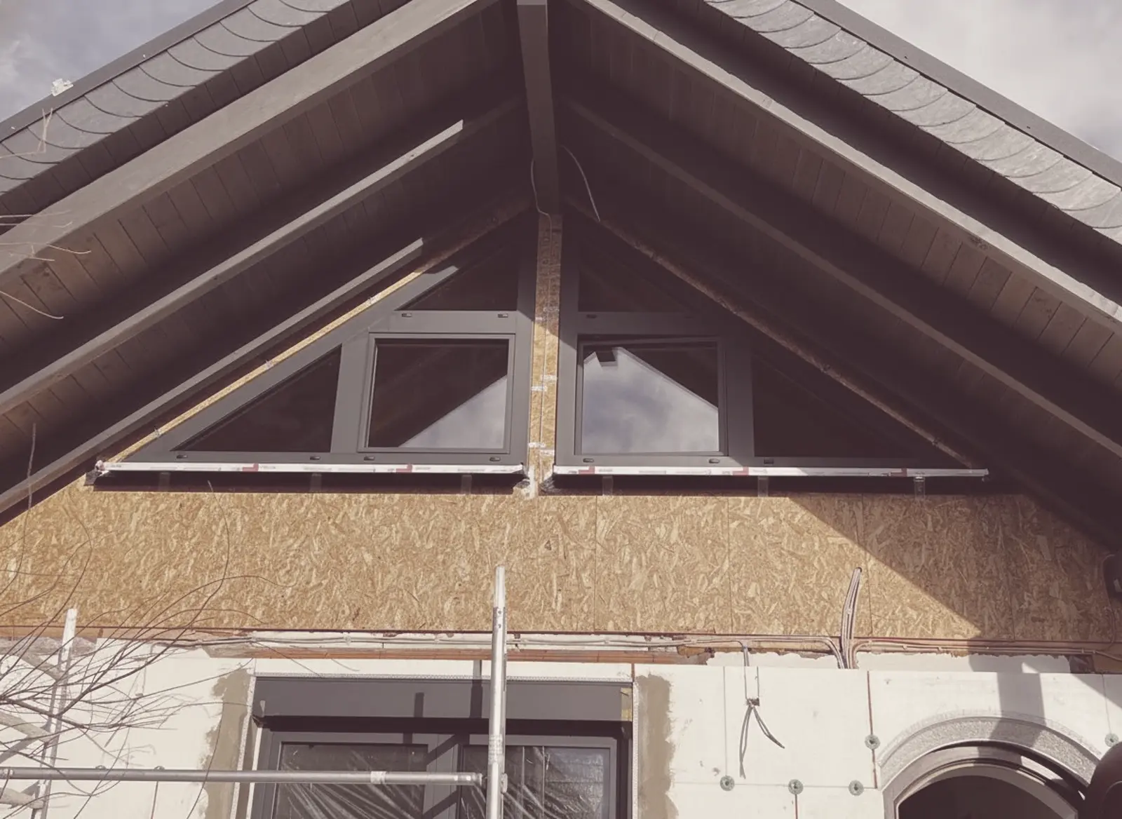 Giebeldreieck-Fenster im Rohbau, von aussen unter dem Dachstuhl gesetzt, Gerüst davor